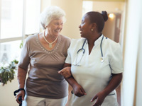 nurse helping senior woman down the hallway
