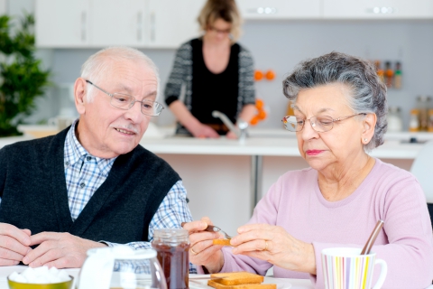 elderly couple eating with nurse in background