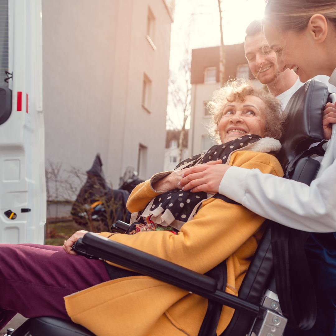 Woman in a wheelchair getting assistance into a vehicle