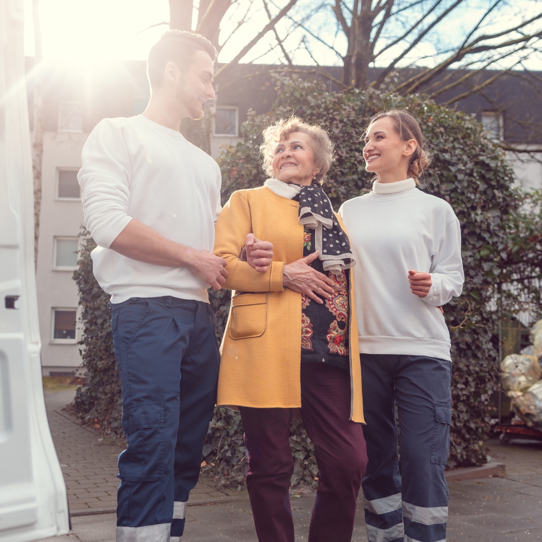 two adults assisting a senior woman